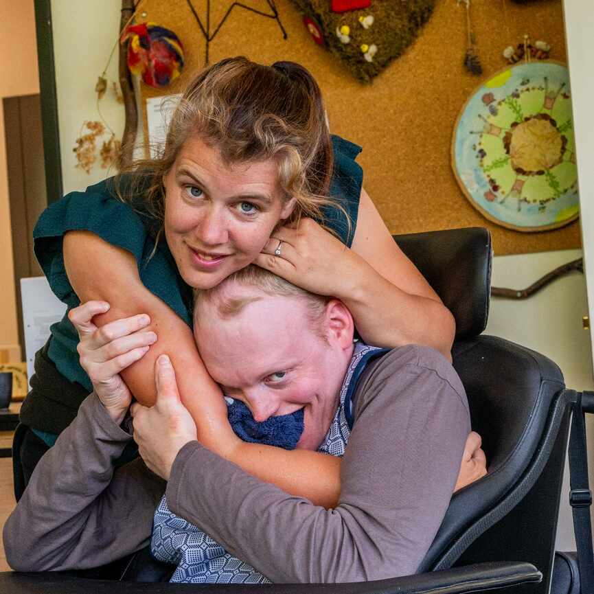 Vrouw knuffelt jongen in rolstoel