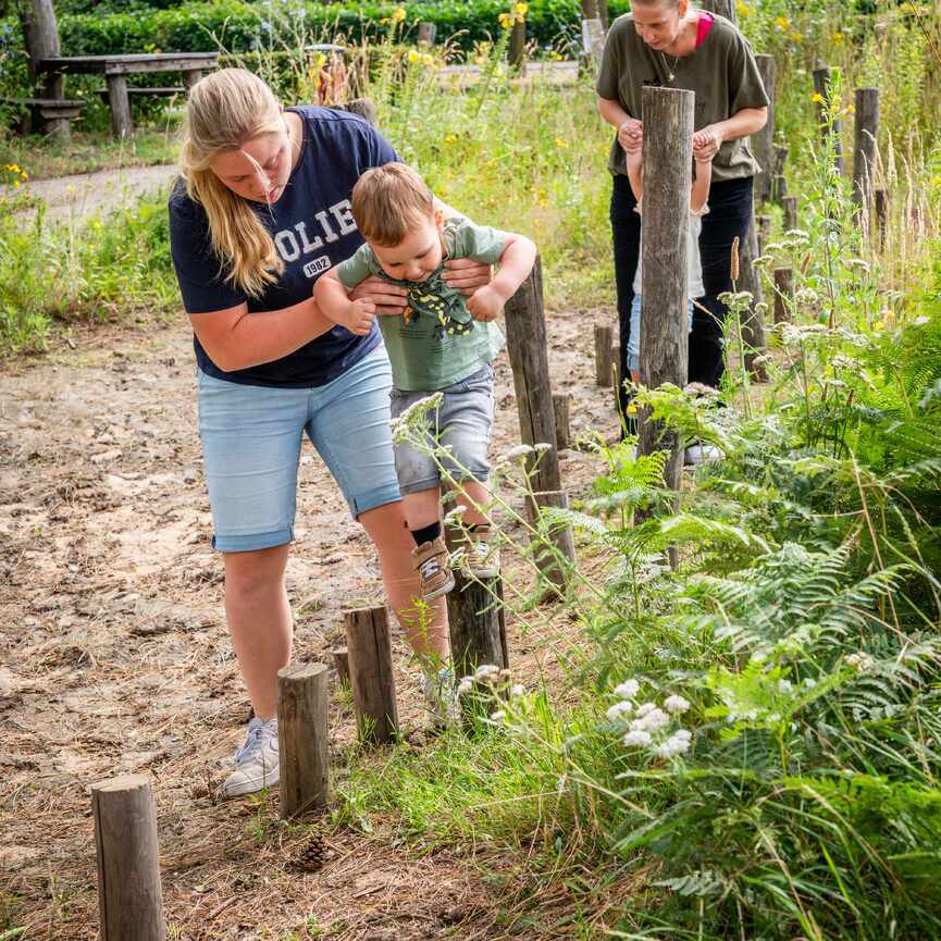 Vrouw helpt jongetje op de paaltjes te staan 2