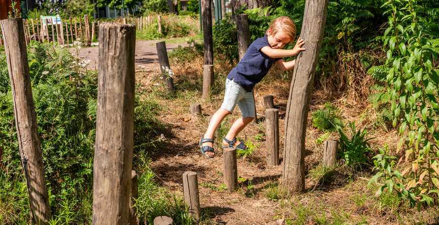 Kind speelt buiten op paaltje