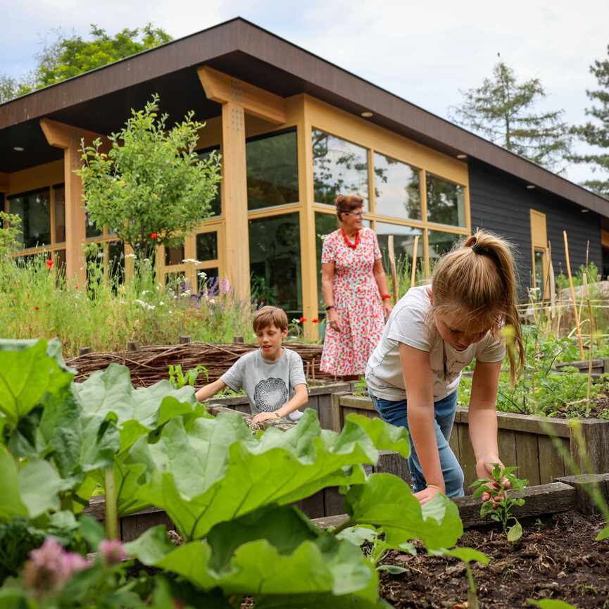 Vrouw met kinderen bij moestuinbak 3