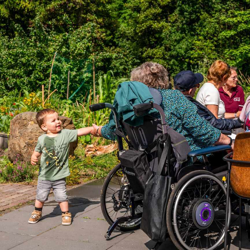Jongetje geeft vrouw in rolstoel een hand