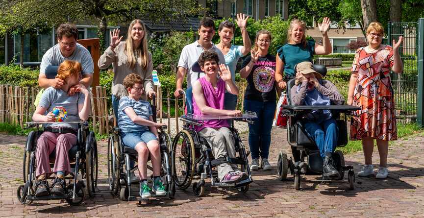 Groepje mensen poseert buiten, een aantal zwaait